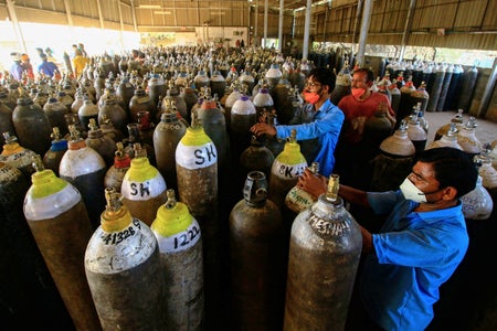 Workers prepares to fill medical oxygen cylinders.