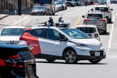 A Cruise autonomous taxi takes a left turn on a busy city street