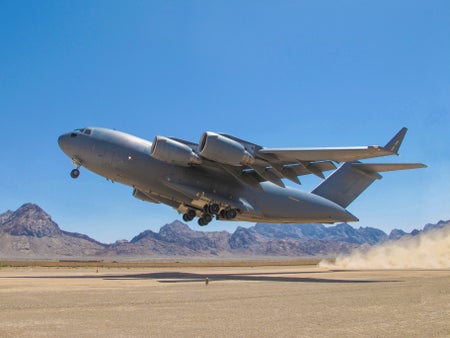 Airforce C17 Globemaster III taking off in desert landscape.