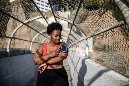 ealthy woman touching phone screen on armband before exercising outdoors