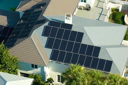 Aerial view of big expensive american building roof with blue solar photovoltaic panels for producing clean ecological electric energy.