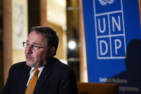 Achim Steiner in orange tie in front of the UNDP logo.